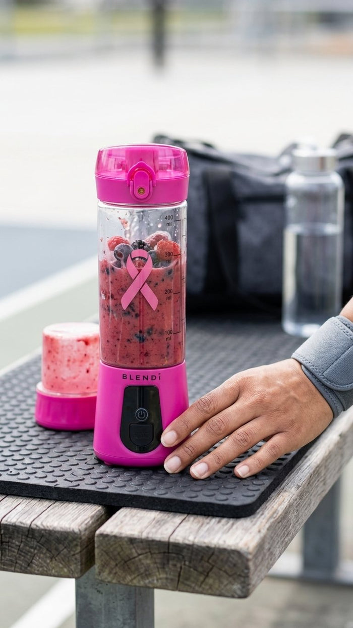 Hot Pink BLENDi Pro+ with a berry smoothie on a gym bench
