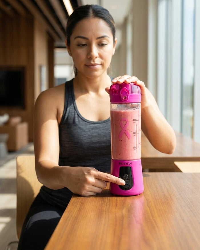 Woman pressing the button on a Hot Pink BLENDi Pro+ at a table