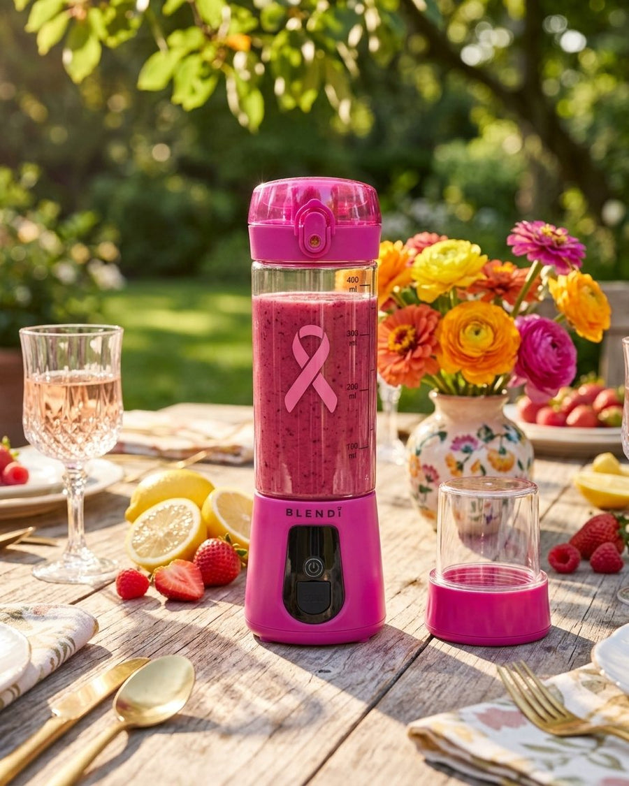 Hot Pink BLENDi Pro+ with a smoothie on a garden table with flowers